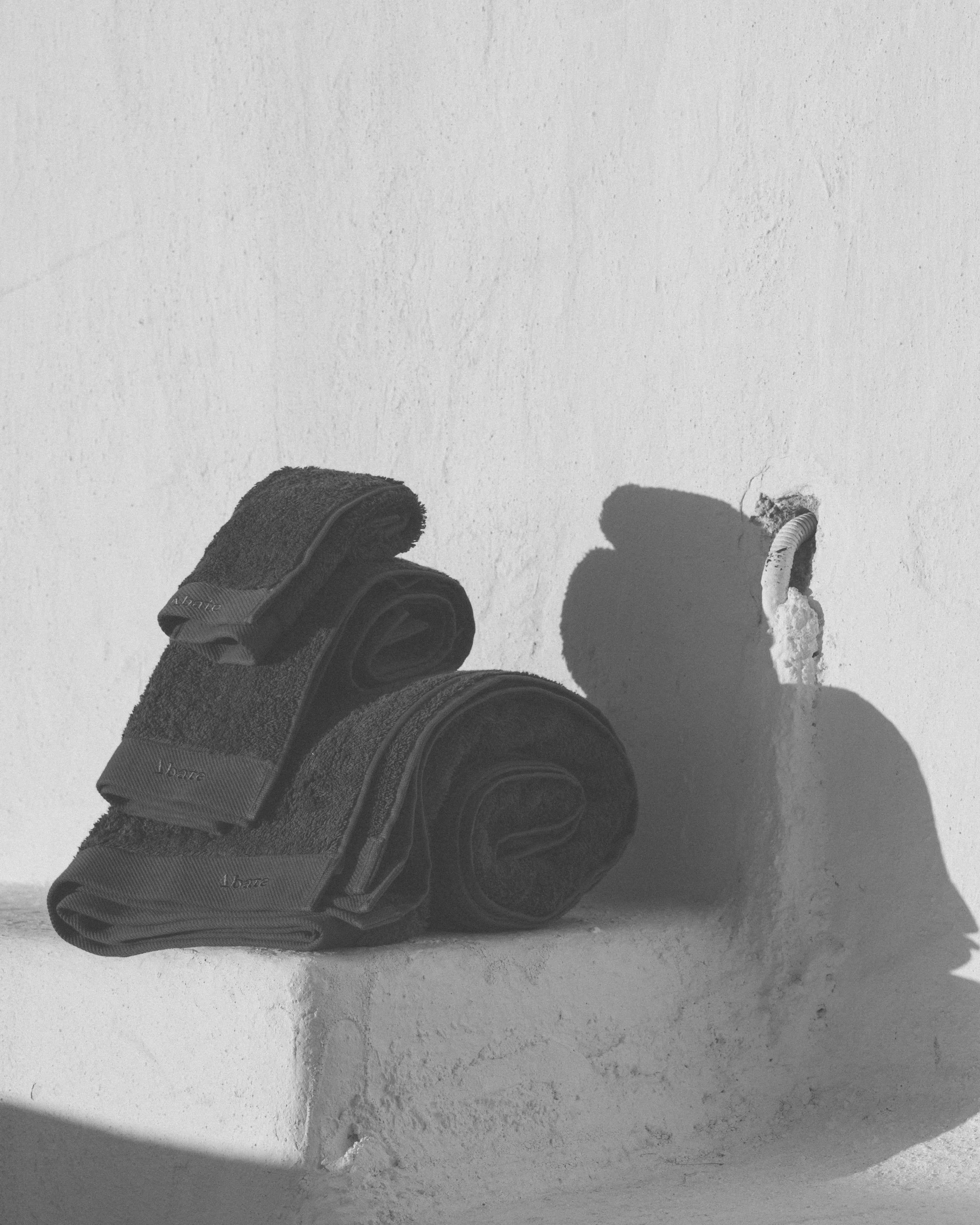 dark grey towels stacked ontop of each other in a black and white image