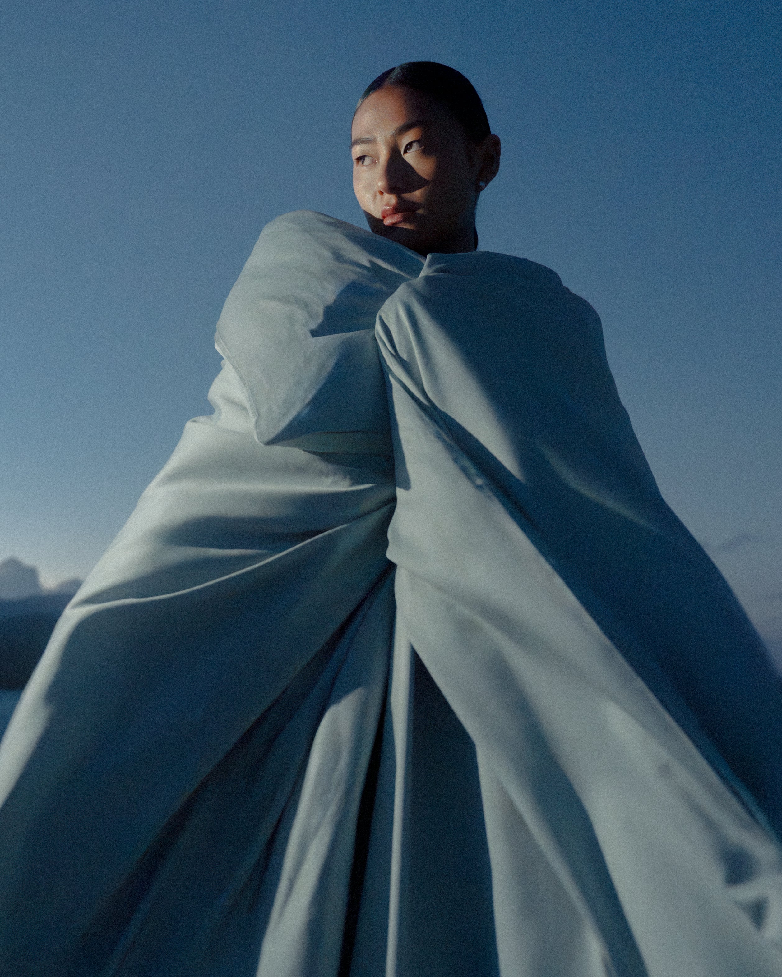 a woman wrapped in a big soft duvet with a blue background